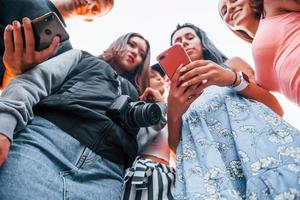 vista de baixo. com telefone. grupo de jovens amigos alegres se divertindo juntos. festa ao ar livre foto