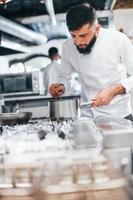 chef de uniforme branco cozinhando comida na cozinha. dia ocupado no trabalho foto