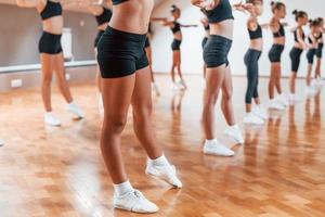 parado na fila. grupo de crianças do sexo feminino praticando exercícios atléticos juntos dentro de casa foto