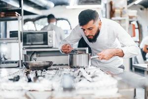 chef de uniforme branco cozinhando comida na cozinha. dia ocupado no trabalho foto