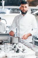 cozinha sopa deliciosa. chef de uniforme branco cozinhando comida na cozinha. dia ocupado no trabalho foto