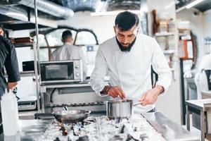 chef de uniforme branco cozinhando comida na cozinha. dia ocupado no trabalho foto