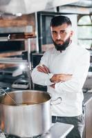 água ferve. chef de uniforme branco cozinhando comida na cozinha. dia ocupado no trabalho foto