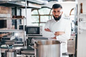 água ferve. chef de uniforme branco cozinhando comida na cozinha. dia ocupado no trabalho foto