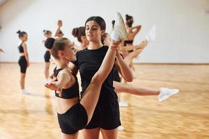 aprendendo com o treinador. grupo de crianças do sexo feminino praticando exercícios atléticos juntos dentro de casa foto