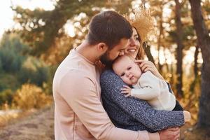 unidade do povo. família feliz de mãe, família e bebê descansa ao ar livre. bela natureza ensolarada de outono foto