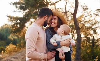 família feliz de mãe, família e bebê descansa ao ar livre. bela natureza ensolarada de outono foto