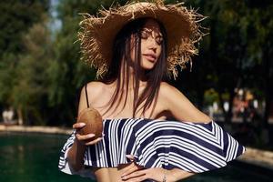 de chapéu de palha. garota se divertir e descansar na piscina durante o dia. concepção de férias foto