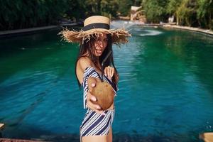 de chapéu de palha. garota se divertir e descansar na piscina durante o dia. concepção de férias foto