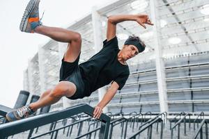 faz parkour. jovem em roupas esportivas tem treino ao ar livre durante o dia foto