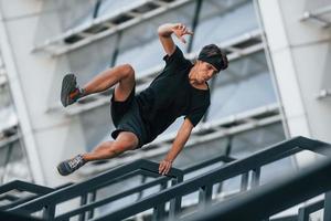 correndo e pulando. jovem em roupas esportivas tem treino ao ar livre durante o dia foto