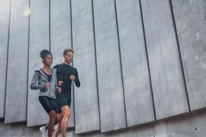 perto da grande parede. homem europeu e mulher afro-americana em roupas esportivas se exercitam juntos foto