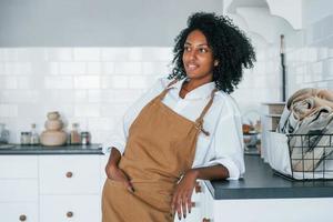 na cozinha. jovem afro-americana com cabelos cacheados dentro de casa foto