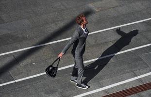 dançando, comemorando o sucesso. jovem empresário em roupa formal cinza está ao ar livre na cidade foto