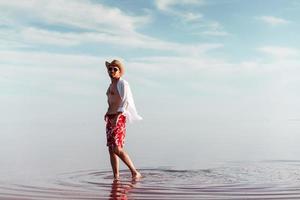 homem de chapéu e roupas casuais caminha no lago na ilha de jarilgach, ucrânia foto
