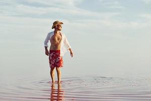 homem de chapéu e roupas casuais caminha no lago na ilha de jarilgach, ucrânia foto