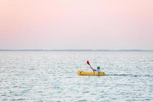 visão distante do homem no barco de cor amarela que está no mar foto