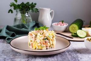 salada olivier em um prato de ingredientes para sua preparação na mesa. lanches de natal foto