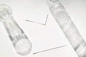 maquete de cartão de visita em branco no vidro com sombra de sobreposição de sombra de folhas naturais no fundo branco, para produto ou apresentação foto