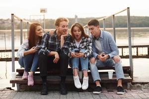 próximo ao lago. grupo de jovens amigos alegres que está ao ar livre se divertindo juntos foto