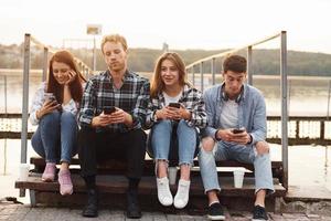 próximo ao lago. grupo de jovens amigos alegres que está ao ar livre se divertindo juntos foto