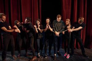 com corda nas mãos. grupo de atores em roupas de cor escura no ensaio no teatro foto