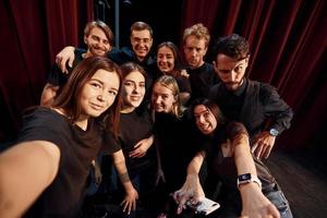 fazendo selfie. grupo de atores em roupas de cor escura no ensaio no teatro foto