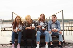 próximo ao lago. grupo de jovens amigos alegres que está ao ar livre se divertindo juntos foto