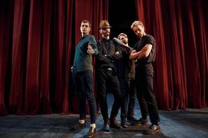 posando para uma câmera. grupo de atores em roupas de cor escura no ensaio no teatro foto