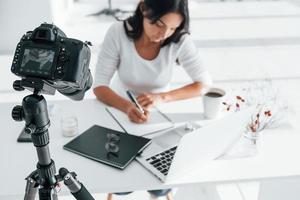 garota de gravação de câmera. jovem freelancer trabalhando dentro de casa no escritório durante o dia foto