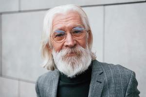 retrato de empresário sênior em roupas formais, com cabelos grisalhos e barba que está ao ar livre foto