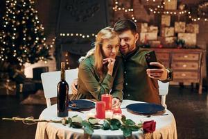 fazendo selfie usando o telefone. jovem casal adorável tem jantar romântico juntos dentro de casa foto