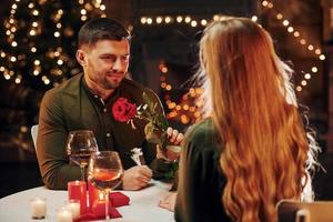 sentado à mesa. jovem casal adorável tem jantar romântico juntos dentro de casa foto