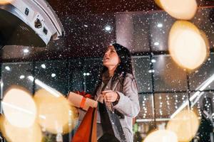 perto do carro com caixa de presente. mulher alegre está ao ar livre na época das férias de natal. concepção de ano novo foto