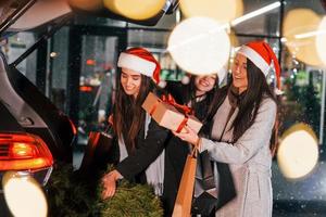 detém abeto. três mulheres alegres passam as férias de natal juntas ao ar livre. concepção de ano novo foto