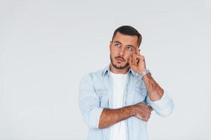 jovem bonito em pé dentro de casa contra um fundo branco foto