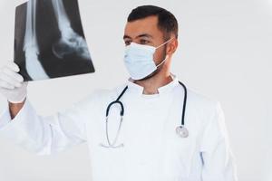 médico com raio-x. jovem bonito em pé dentro de casa contra um fundo branco foto