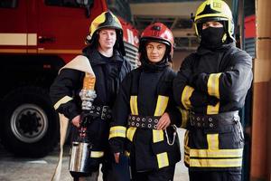 posando para uma câmera. grupo de bombeiros em uniforme de proteção que está na estação foto