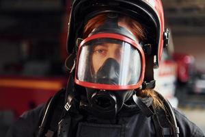 vista de perto. bombeira em uniforme de proteção em pé perto de caminhão foto