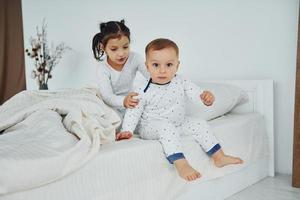 duas crianças se divertem enquanto estão deitadas na cama. interior e design do lindo quarto moderno durante o dia foto