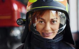 vista de perto. bombeira em uniforme de proteção em pé perto de caminhão foto