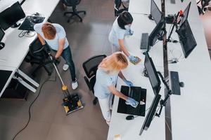 vista do topo. grupo de trabalhadores limpa escritório moderno juntos durante o dia foto