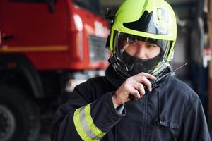 bombeiro masculino em uniforme de proteção em pé perto do caminhão foto