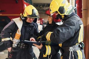 com bloco de notas. grupo de bombeiros em uniforme de proteção que está na estação foto