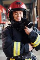 lindo gato preto. bombeira em uniforme de proteção em pé perto de caminhão foto