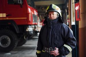 bombeiro masculino em uniforme de proteção em pé perto do caminhão foto