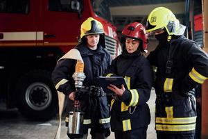 com bloco de notas. grupo de bombeiros em uniforme de proteção que está na estação foto