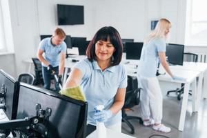 grupo de trabalhadores limpa escritório moderno juntos durante o dia foto