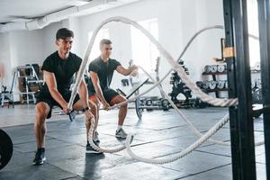 jovens com formas corporais esportivas fazendo crossfit usando nós foto