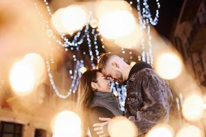 iluminação artificial por guirlandas. feliz casal multirracial juntos ao ar livre na cidade comemorando o ano novo foto